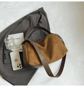 Detail of a brown suede baguette shoulder bag with smooth leather trim and gold rivets