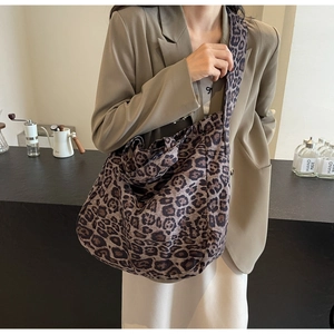 Detailed view of leopard print tote bag on shoulder in a stylish cafe setting