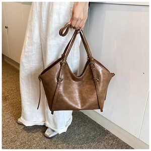 Detailed macro of a vintage brown leather tote bag with stylish metal buckles
