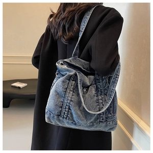 Detail of vintage washed denim tote bag showing wide strap and metallic button accents