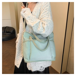 Detailed view of mint green canvas tote bag featuring adjustable shoulder strap and pockets