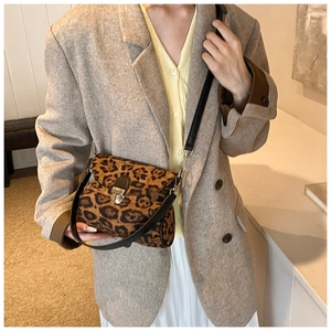 Close-up of leopard print crossbody bag with silver buckle on a stylish model