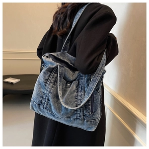 Detail of vintage washed denim tote bag showing distressed texture and zipper pockets