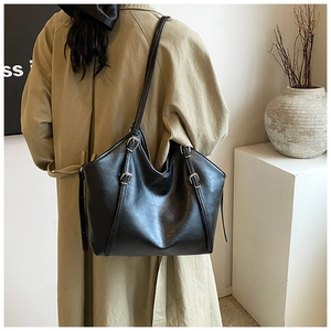 Detail of black leather tote bag with silver buckle strap and retro textured finish