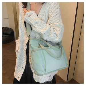 Detailed view of mint green canvas tote bag worn by a model in a cozy indoor setting