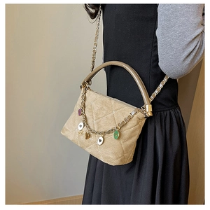 Detail of beige quilted suede handbag with colorful enamel charms and chain strap