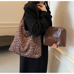 Détail du sac cabas imprimé léopard et pochette en cuir marron porté par un mannequin