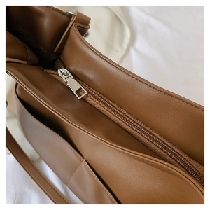 Macro shot of the durable metal zipper and side pocket on this brown leather tote bag