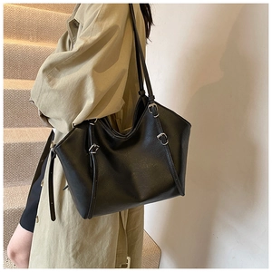 Close-up of black matte tote bag featuring silver buckles and spacious leather texture