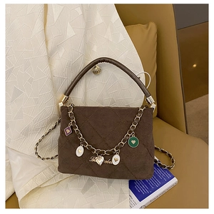 Detailed shot of dark brown quilted suede handbag with colorful heart charms and gold chain