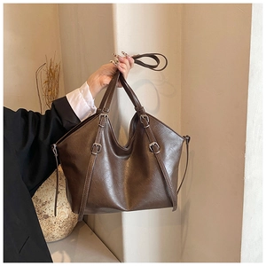 Detail of vintage brown tote bag showing leather texture and silver buckle accents