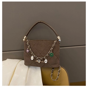 Close-up of brown quilted bag featuring heart charms and gold chain strap details