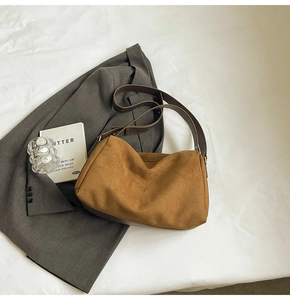 Detail view of suede leather baguette bag placed on a grey suit with minimalist props