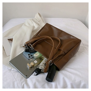 Top view of large brown leather tote bag filled with a tablet and everyday essentials