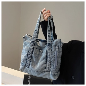 Close-up of vintage blue denim tote bag with metal snap pocket and durable handles