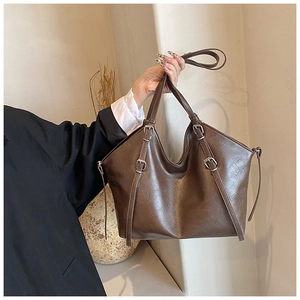 Detail view of large brown tote bag showing vintage lychee texture and metal buckles
