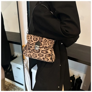 Detailed view of women's leopard print shoulder bag with silver clasp on black coat