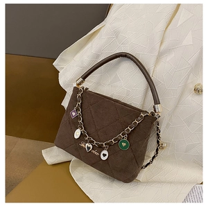 Detail of dark brown quilted suede handbag with decorative heart charms and metal chain