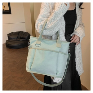 Detail of mint green canvas tote bag with front pockets and wide shoulder strap