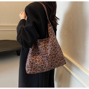 Grand sac fourre-tout à motif léopard porté à l'épaule avec un long manteau en laine noir