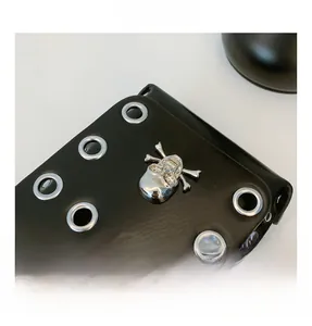 Detail shot of black leather texture with silver metal eyelets and skull crossbones stud