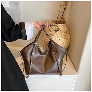 Detail of dark brown textured tote bag with silver buckles and retro commuter design