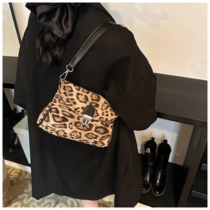 Detail view of leopard print shoulder bag with black leather strap and silver twist lock