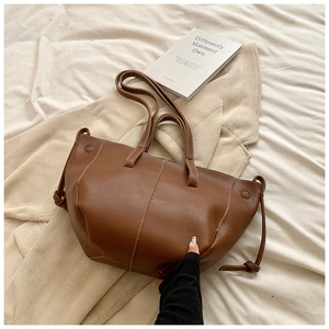 Detailed macro view of a brown pebbled leather tote bag with elegant white stitching