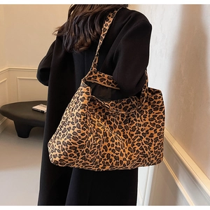 Detail view of large leopard print tote bag styled with a black coat in a modern interior