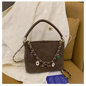 Detail of brown quilted bag with colorful heart charms and golden chain strap