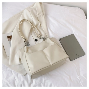 Detailed macro view of cream tote bag with dual front pockets and silver chain link strap