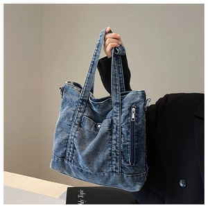 Detailed shot of large denim tote bag featuring external zipper pocket and metal snap button