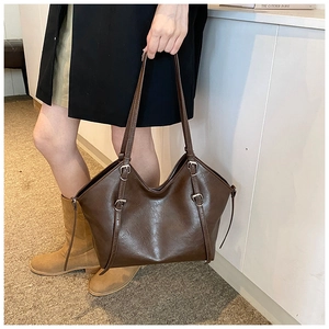 Detail of vintage oil wax leather tote bag featuring adjustable buckle straps and smooth texture