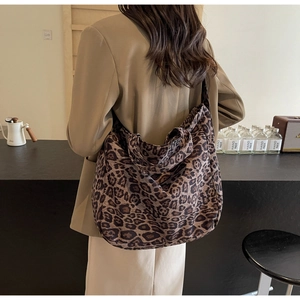 Model wearing a large leopard print tote bag over the shoulder in a minimalist indoor setting