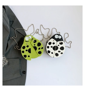 Detail of ladybug-shaped mini bags in green and cream PU leather with metal bead chains