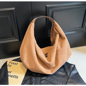 Close-up of brown suede hobo bag texture with black metal zipper on leather background