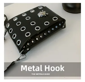 Detailed close-up of the silver hardware hook and rivets on the black punk skull crossbody bag