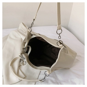 Close-up of cream tote bag featuring silver chain straps and dark brown fabric lining
