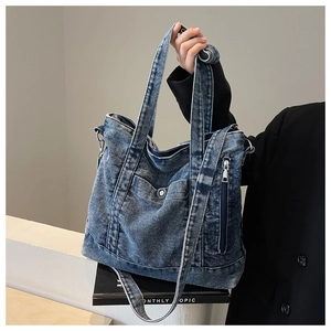 Detail view of denim tote bag with metal snap pocket and adjustable crossbody strap