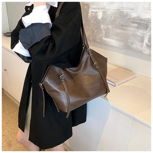 Detail view of large dark brown retro tote bag with silver adjustable buckle on soft leather