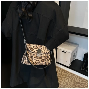Detail of leopard print crossbody bag with silver buckle and textured animal pattern