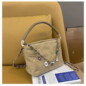 Detailed close-up of khaki quilted crossbody bag with heart charms on yellow background