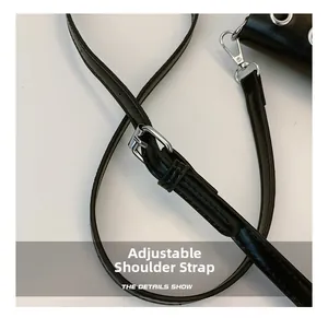 Detail of adjustable black leather shoulder strap with silver buckle and metal hooks