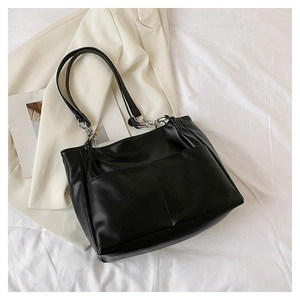 Close-up of black PU leather tote bag featuring dual front pockets and metal chain strap