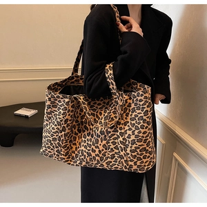 Detailed close-up showing leopard print canvas texture and wide shoulder straps on tote bag