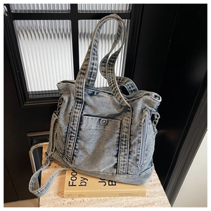 Detail of blue denim tote bag with side zipper pocket and adjustable shoulder strap