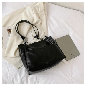 Detail of black leather tote bag with V-shaped stitching and silver metal chain straps