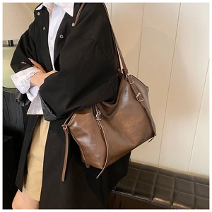 Detail view of large dark brown tote bag with leather texture and metal buckle accents