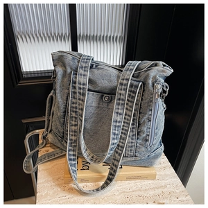 Detail of light blue denim tote bag with adjustable strap on a marble display