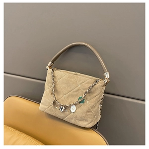 Detail of beige quilted handbag with elegant gold chain and heart-shaped metal charms
